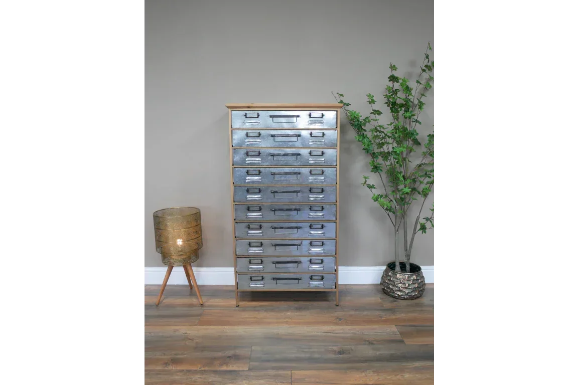 Tall industrial metal chest of drawers with label slots, styled with lamp and potted plant