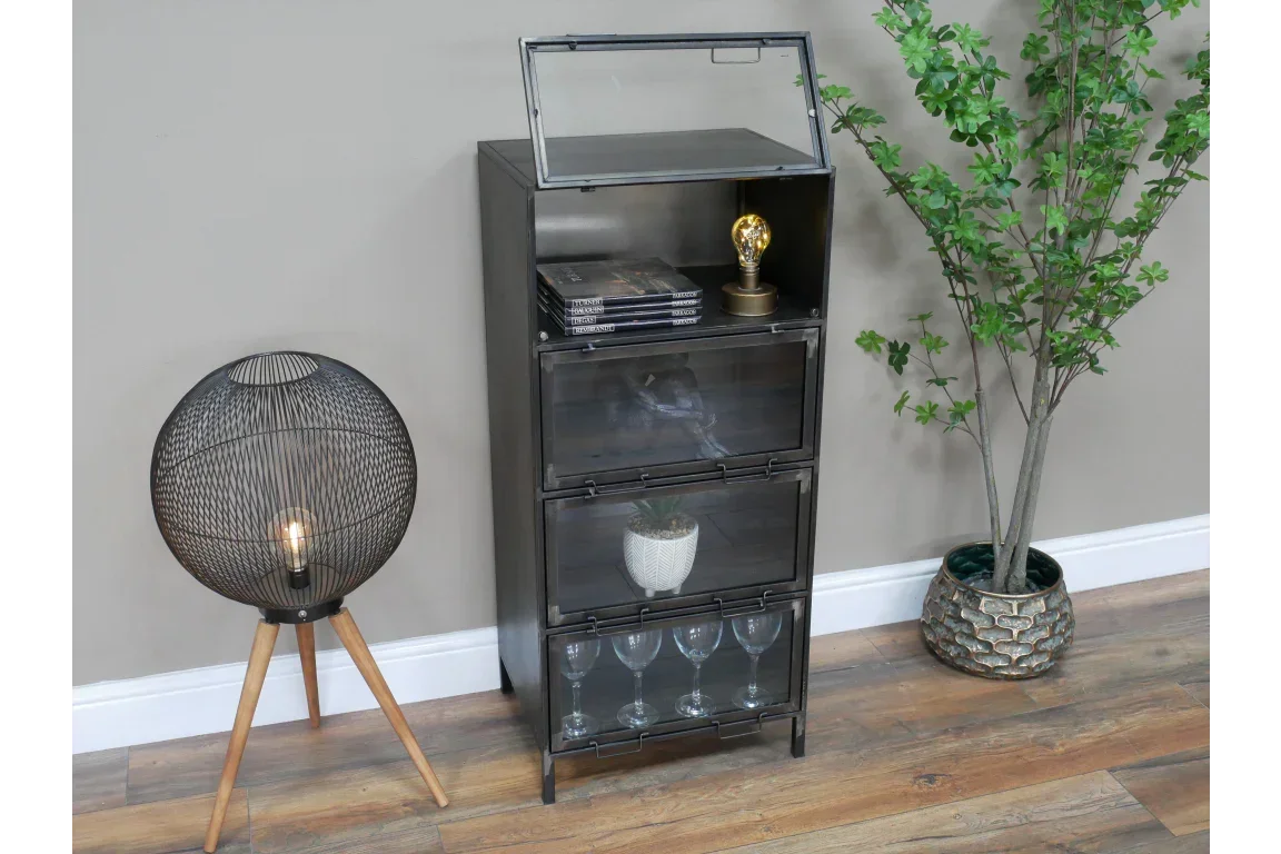 Industrial metal display cabinet with glass doors, shown with books, lamp, and glassware