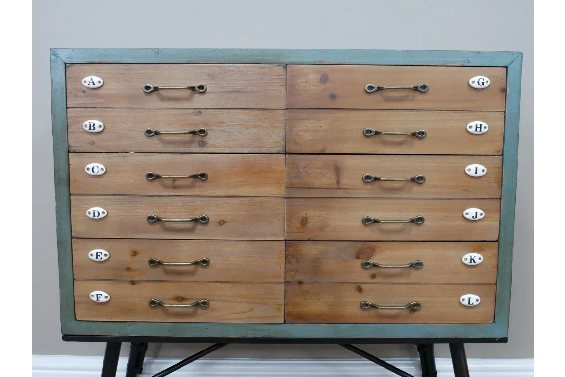 Wooden chest of drawers with twelve labelled drawers and metal handles on black legs
