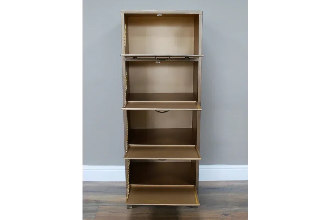 Tall gold metal shelving unit with four open shelves, chain detail on sides, against grey wall