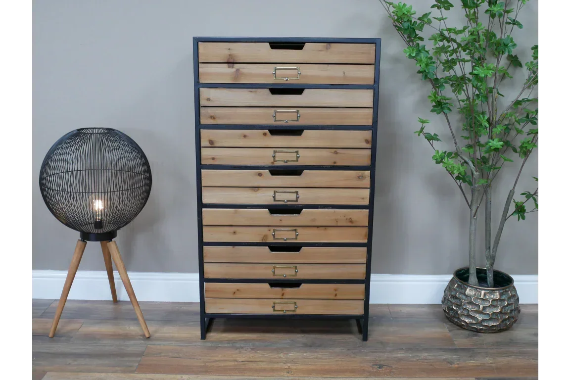 Industrial wood chest of drawers with black frame beside tripod floor lamp and potted plant