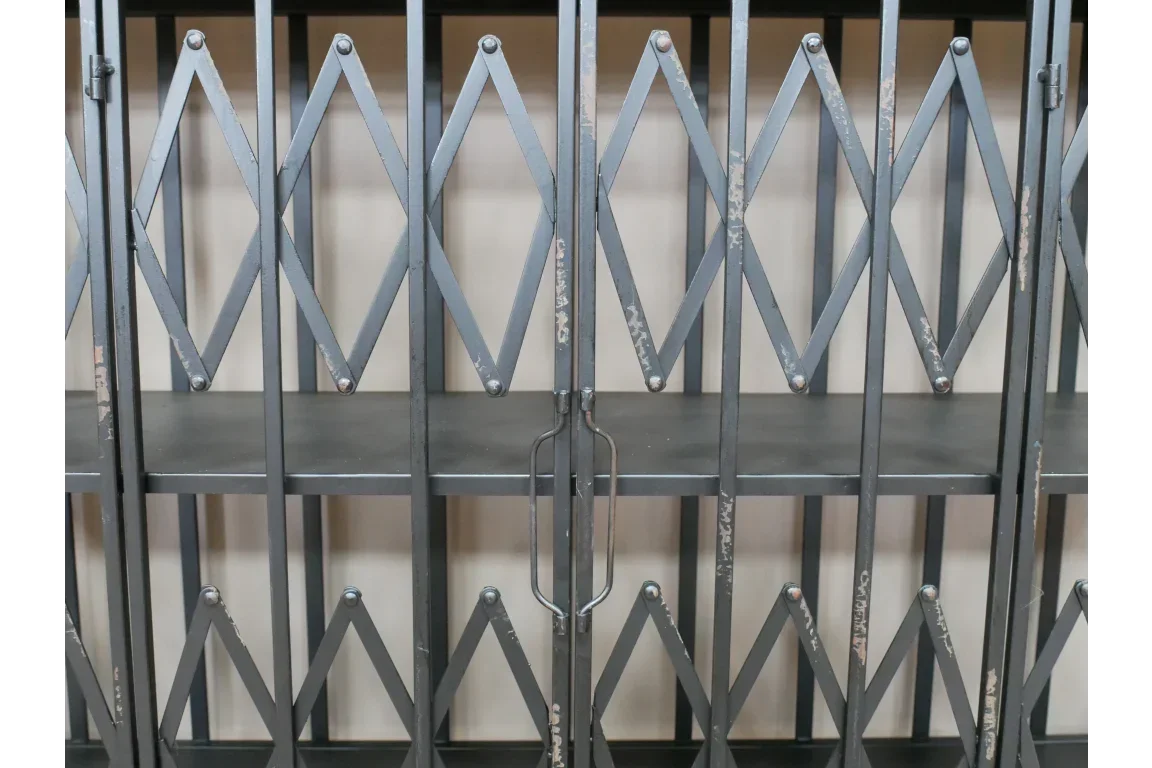 Industrial metal shelving unit with crisscross steel doors and central handles