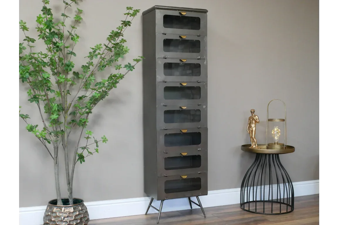 Tall industrial storage cabinet with metal legs and glass doors beside decorative side table