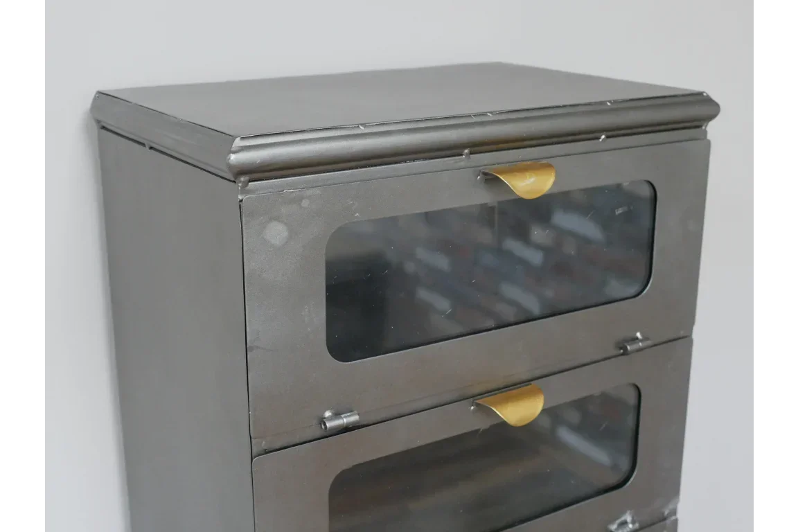 Metal storage cabinet with glass doors and brass handles, side angle view