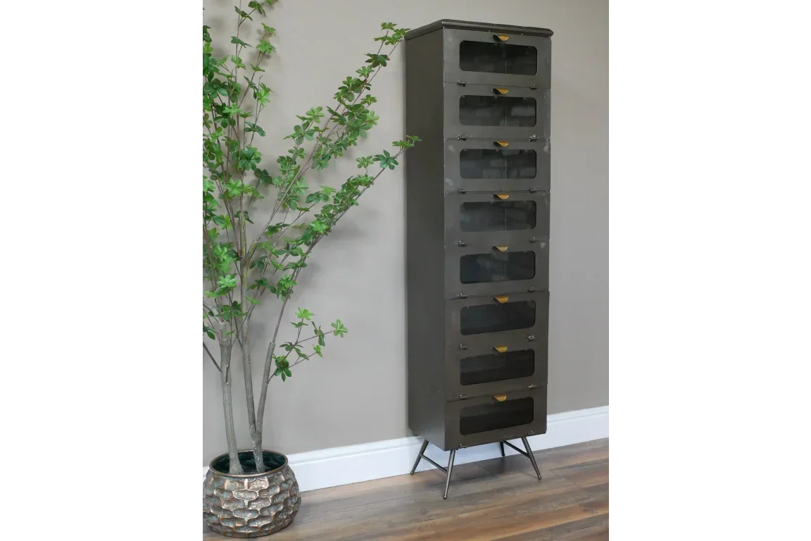 Tall metal storage cabinet with mesh doors and angled legs beside potted plant on wood floor
