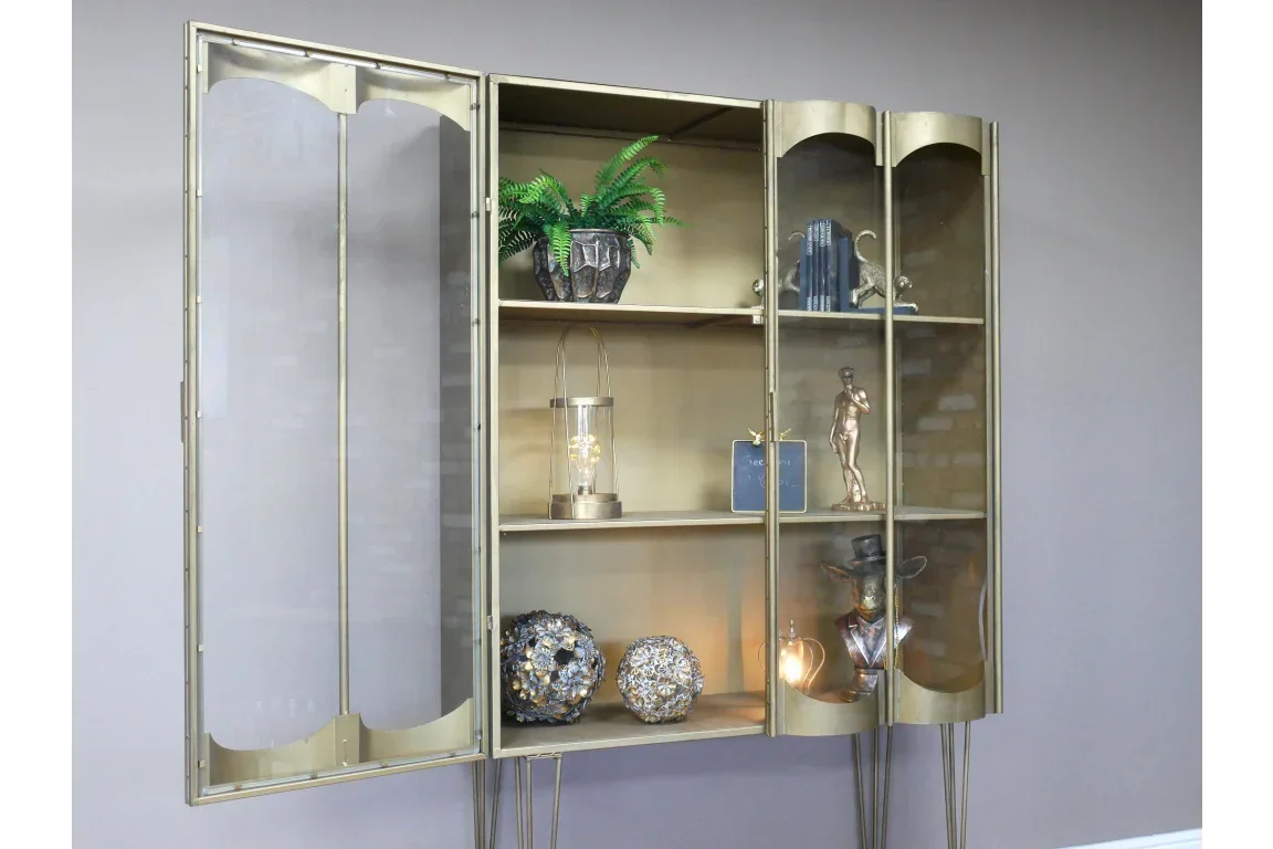 Gold glass display cabinet with shelves holding books, sculptures, decor, and plants