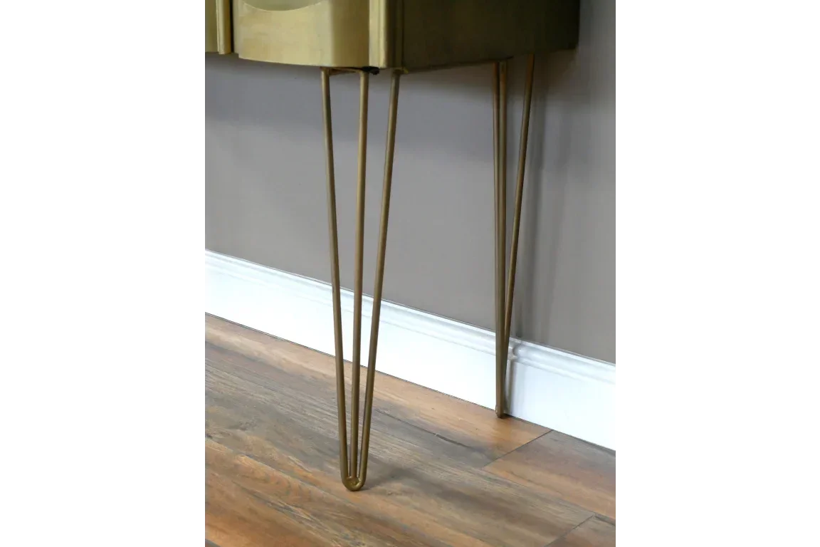Gold metal hairpin legs on a wooden side table against a grey wall and wood floor