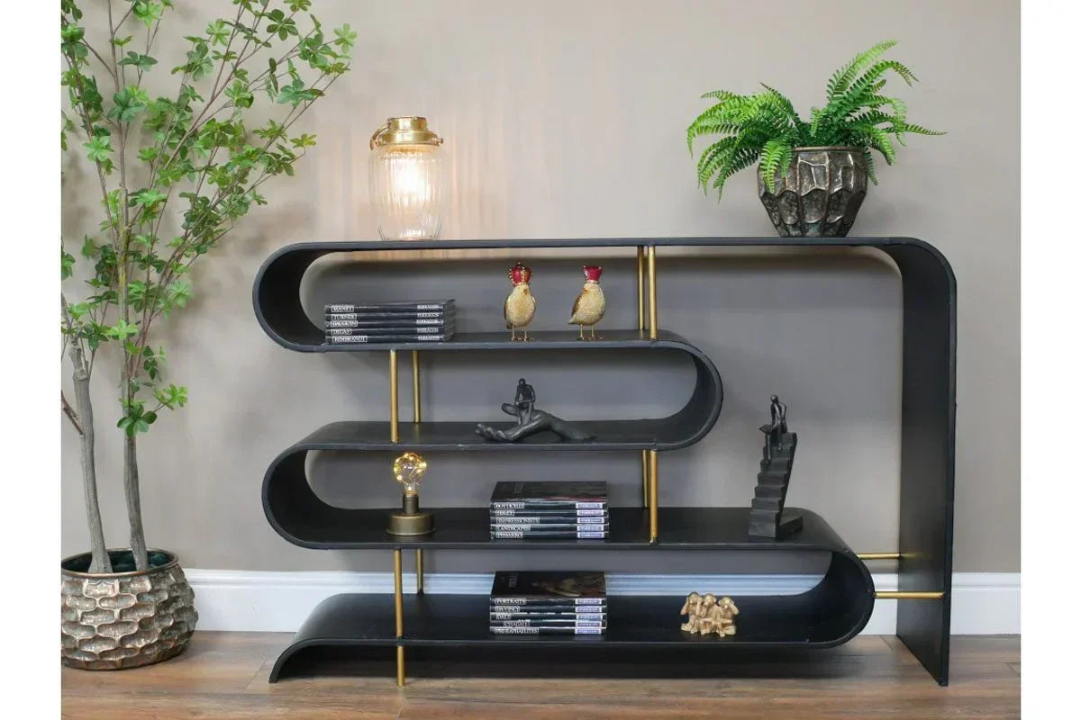 Black metal bookshelf with gold supports, holding books, plants, and decorative ornaments