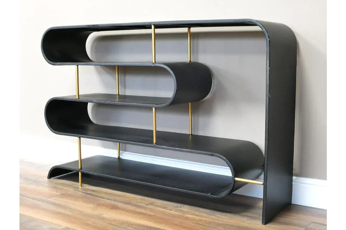 Black metal shelving unit with gold supports and curved edges against wall on wooden floor