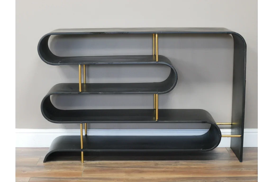 Black metal console table with curved shelves and gold supports against beige wall