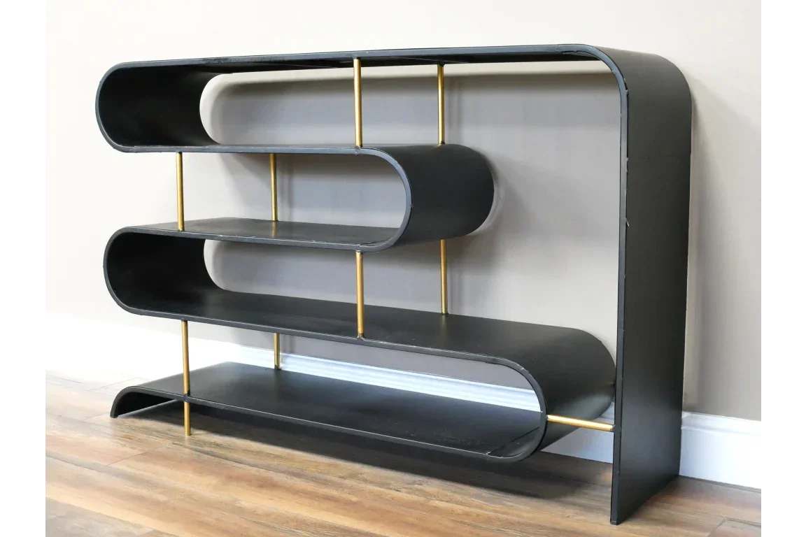 Black metal bookshelf with gold supports and curved shelves against wall on wooden floor