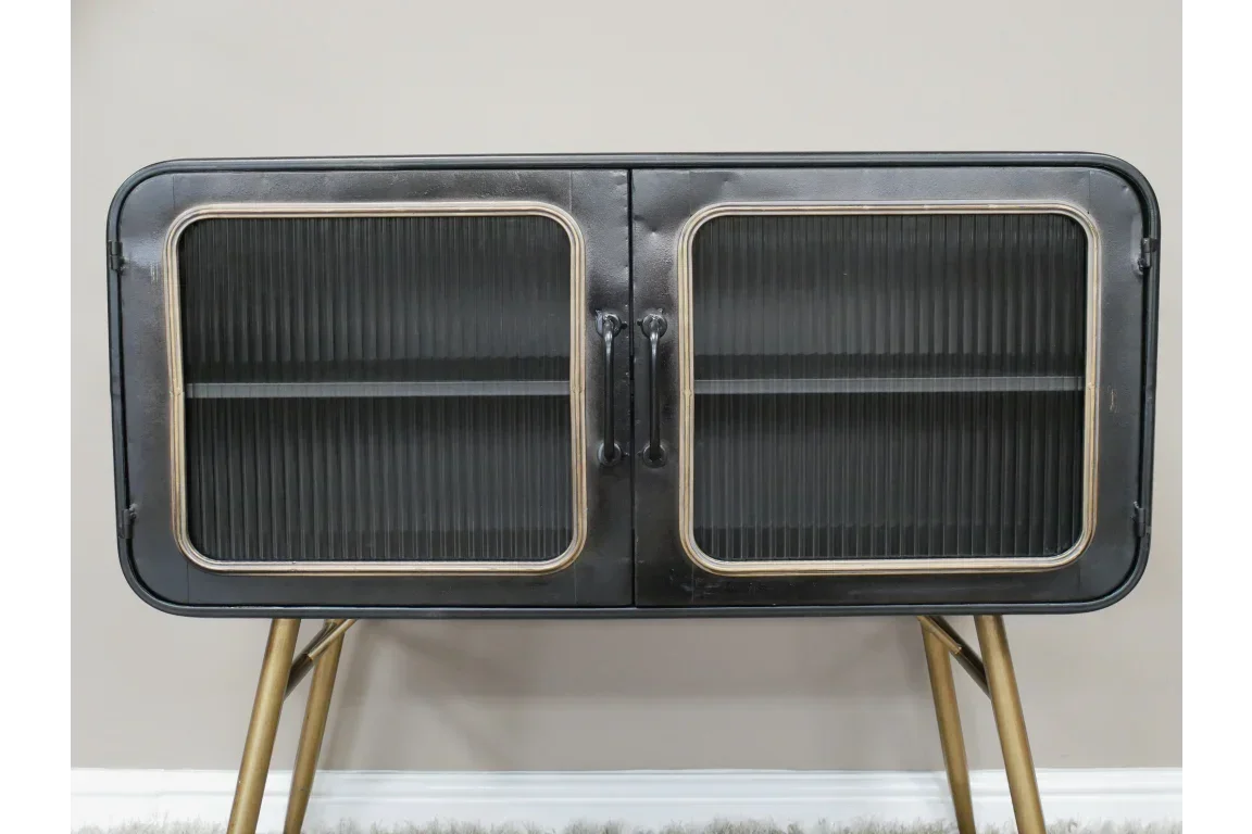 Black metal sideboard with glass doors and gold legs against beige wall