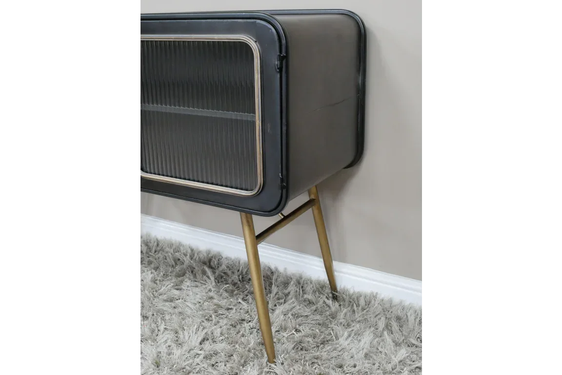 Black metal sideboard with ribbed glass door and gold angled legs on shaggy rug