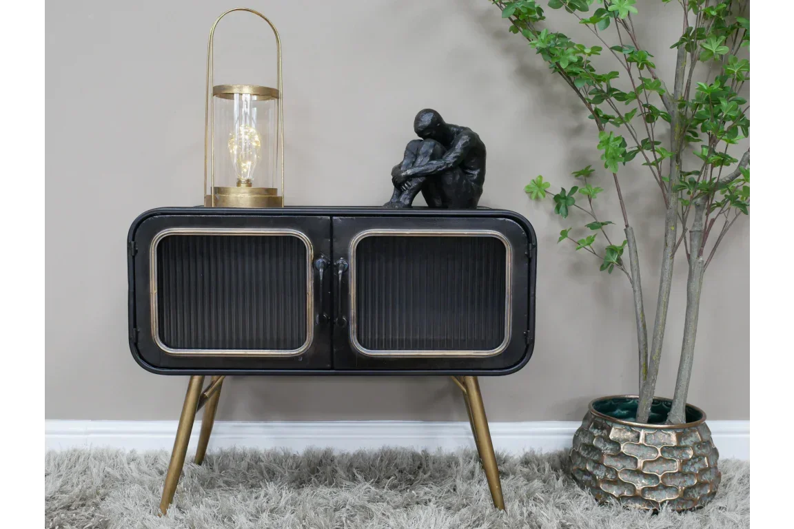 Black sideboard cabinet with gold legs, glass doors, table lamp and figurine decor