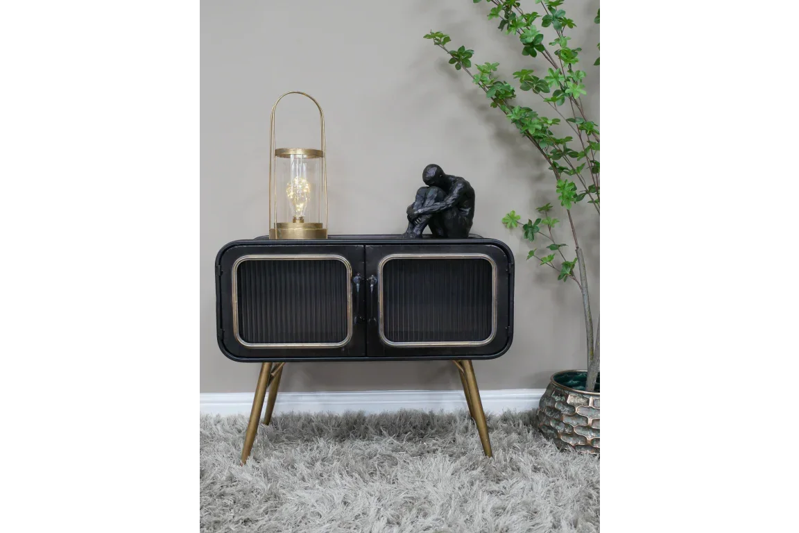 Black sideboard with gold legs, glass lamp and abstract sculpture, living room setting
