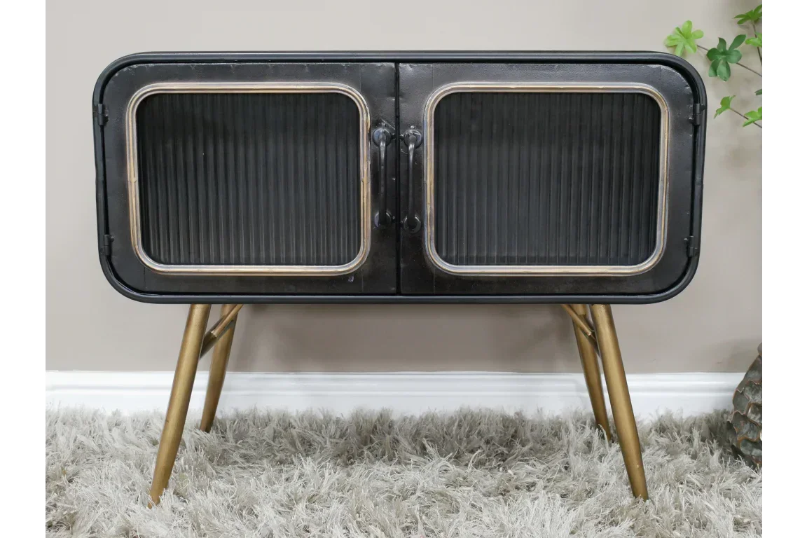 Black metal sideboard with glass doors and gold angled legs on shaggy rug