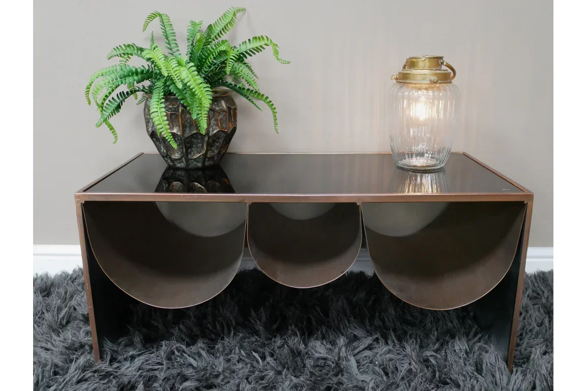 Modern glass top coffee table with geometric metal base, plant and lantern styled on top