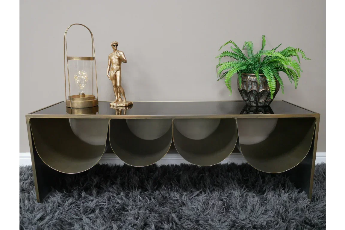 Gold and black metal coffee table with decorative ornaments and potted fern on top