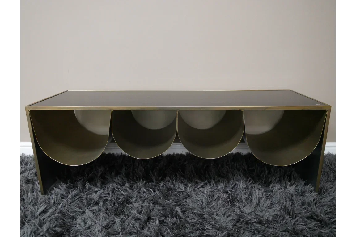 Gold metal coffee table with semi-circular storage compartments on grey rug
