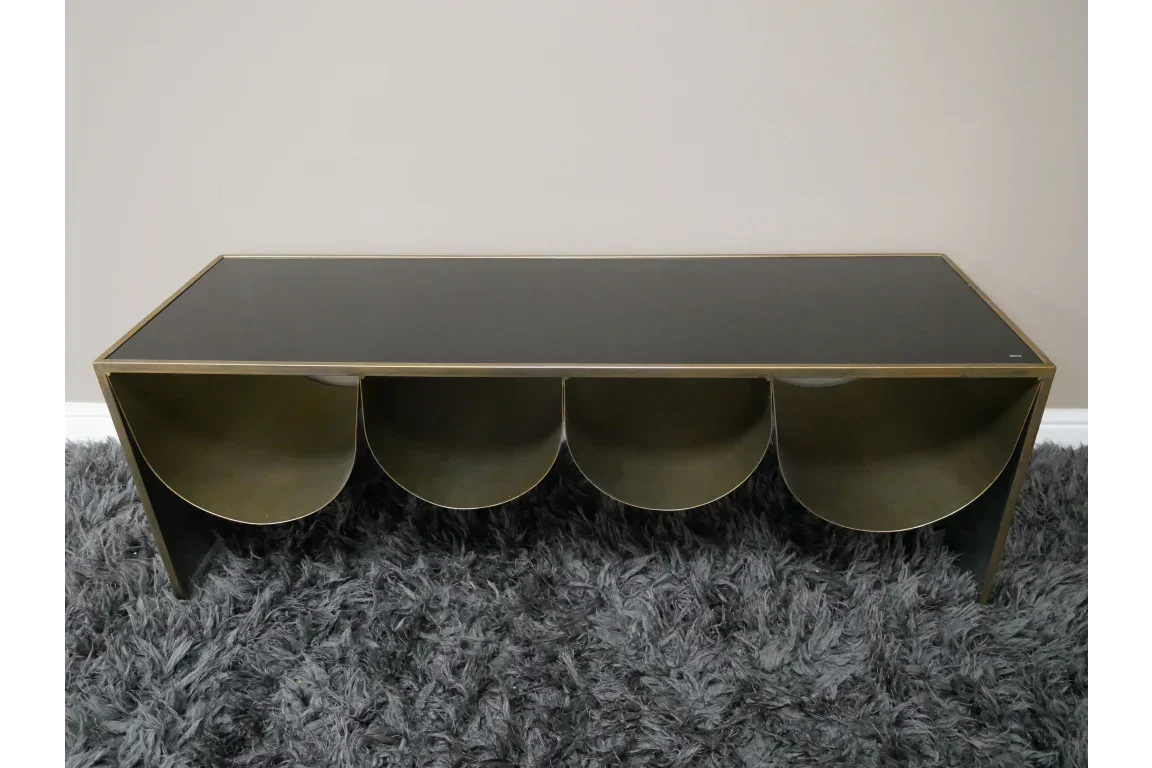 Modern coffee table with black glass top and gold metal storage compartments on grey rug