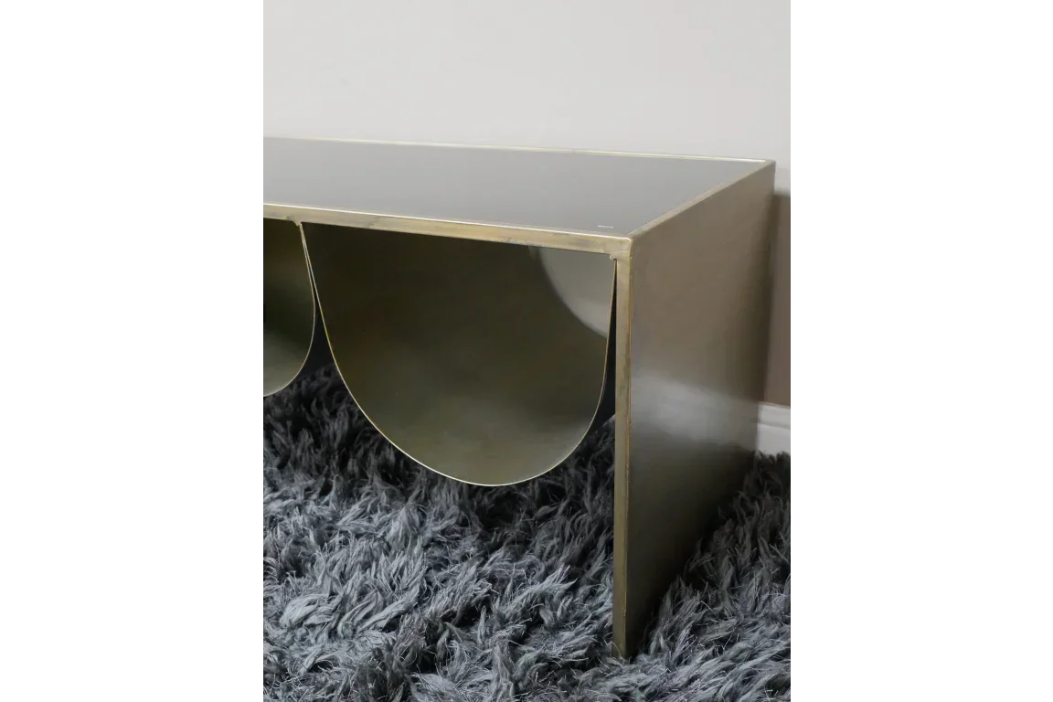 Brass metal coffee table with semicircular shelf detail on grey shaggy rug