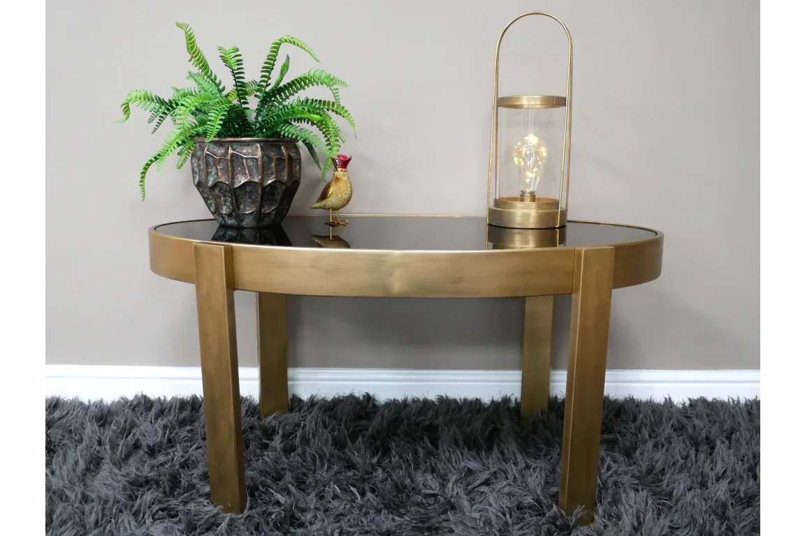 Gold console table with black glass top, potted plant, lamp and ornament on fluffy rug