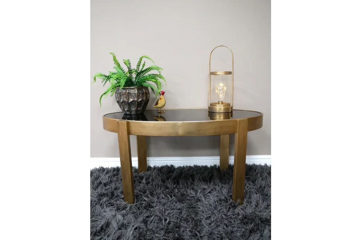 Round gold metal side table with black glass top, plant, lamp and ornament on grey rug