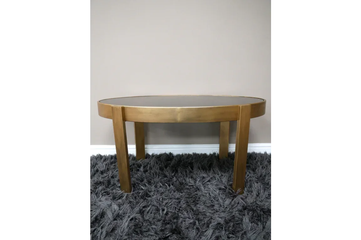 Round gold coffee table with glass top on grey shaggy rug