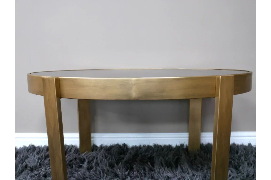 Gold metal coffee table with glass top on grey shaggy rug, modern living room furniture