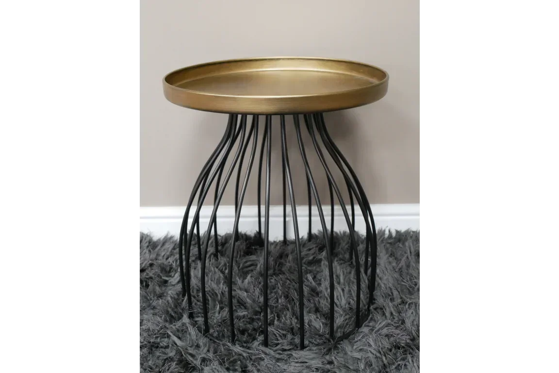 Round gold metal side table with black wire base on grey rug