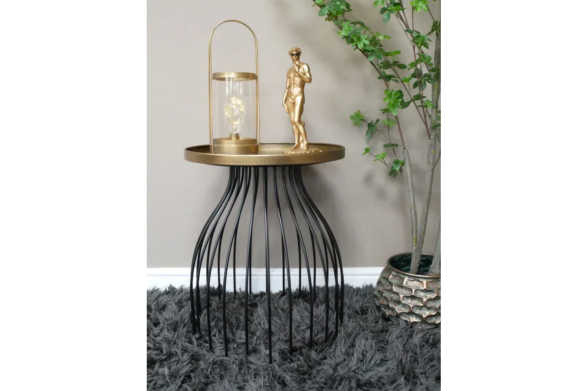 Round metal side table with gold tray top and decorative ornaments on grey rug