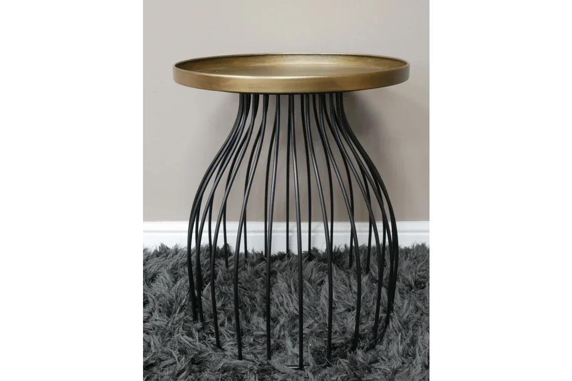 Round metal side table with gold top and black wire frame on grey shaggy rug