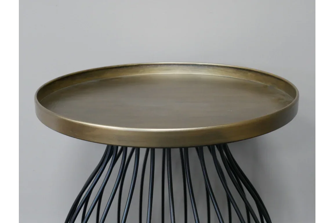 Round metal side table with gold tray top and black wire base against grey background