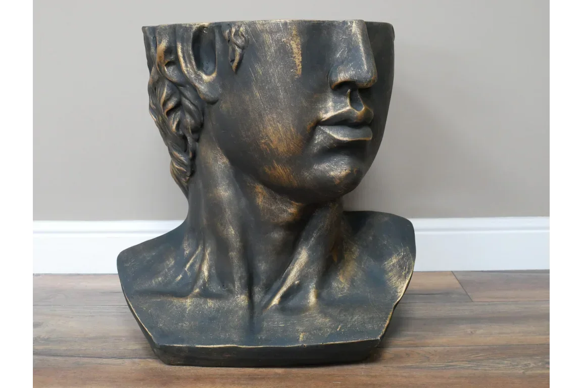 Black and gold decorative head planter with classical bust design on wooden floor