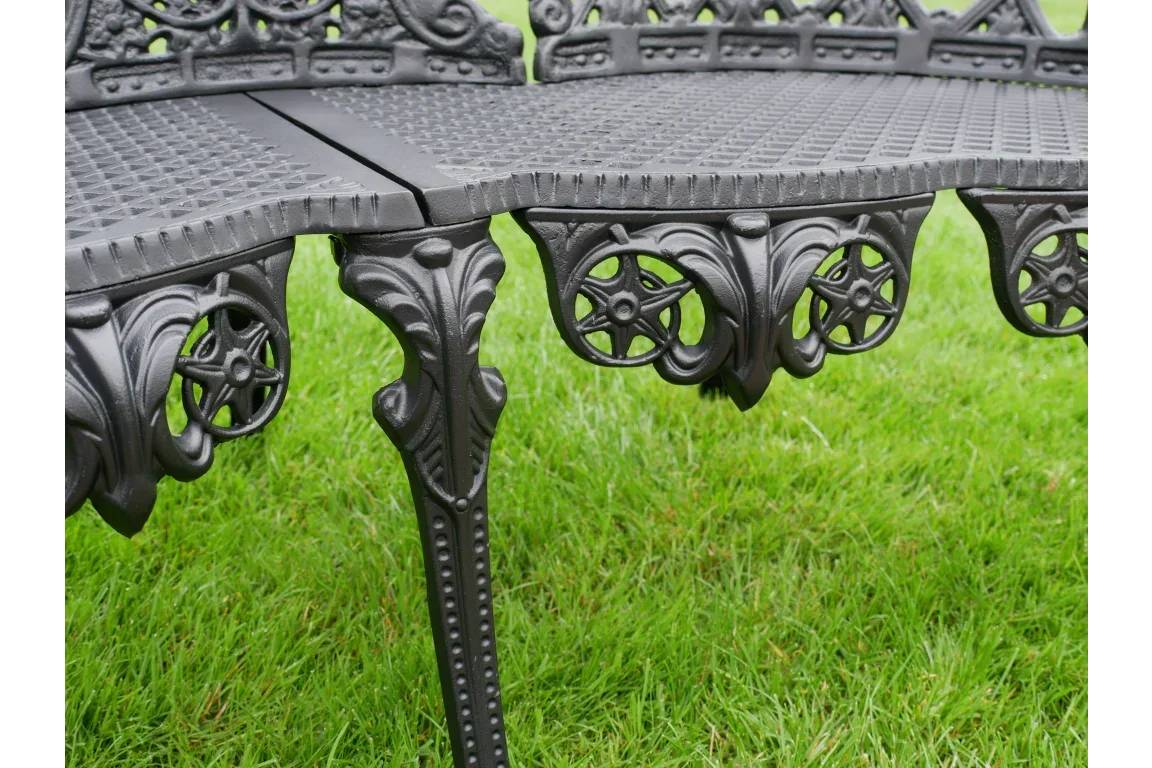 Black cast iron garden bench leg with ornate detailing on green grass