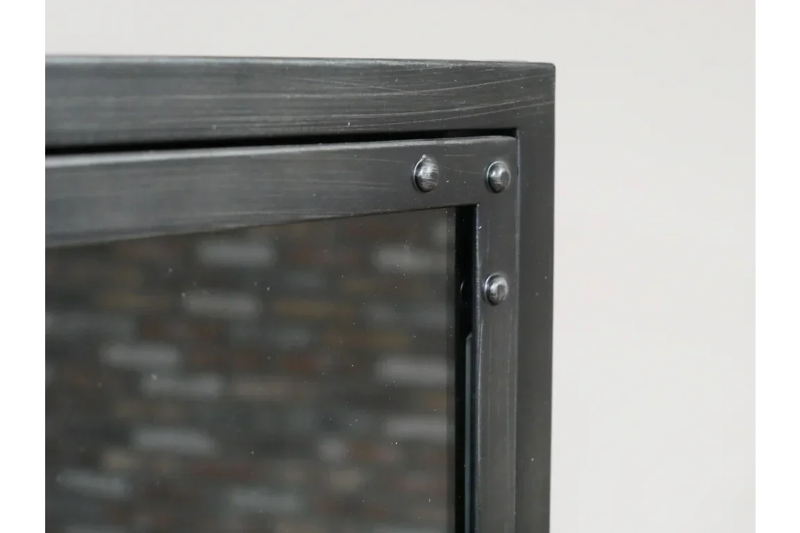 Close-up of black metal cabinet corner with rivets and glass panel