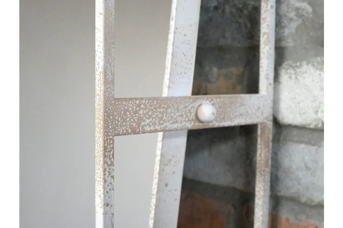 Close-up of speckled metal ladder shelf against brick wall, showing textured finish