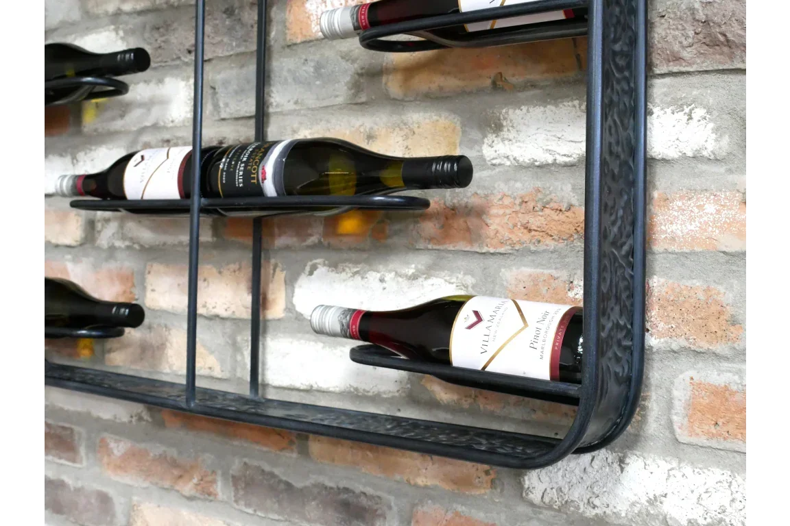 Wall mounted metal wine rack holding bottles against exposed brick background
