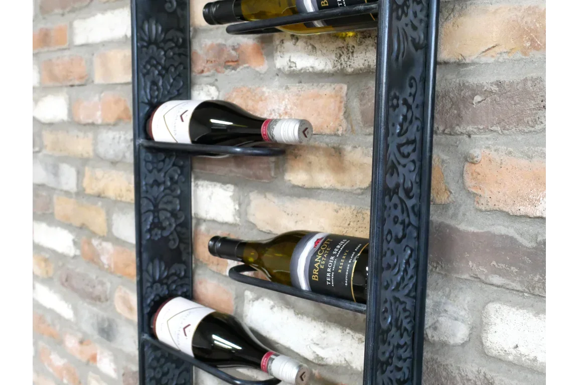 Black metal wall wine rack with floral pattern holding wine bottles on brick wall