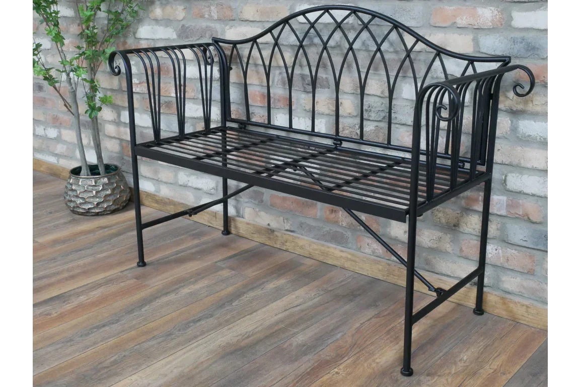 Black metal garden bench with decorative backrest and armrests on wooden floor