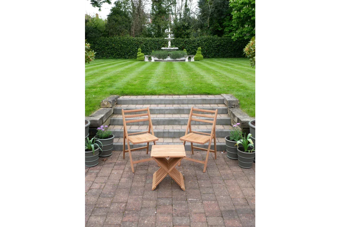Wooden garden bistro set with two folding chairs and square table on brick patio