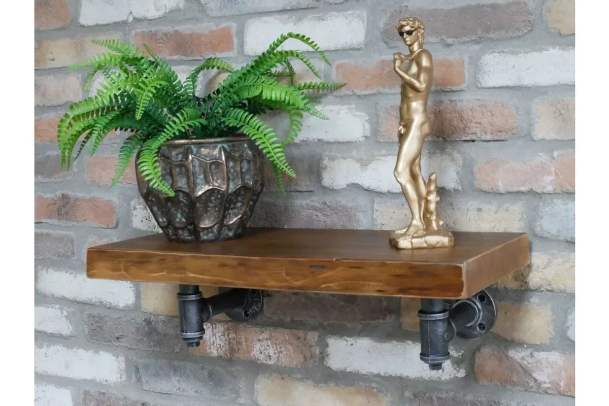 Industrial wood wall shelf with metal pipe brackets, plant pot, and gold statue decor