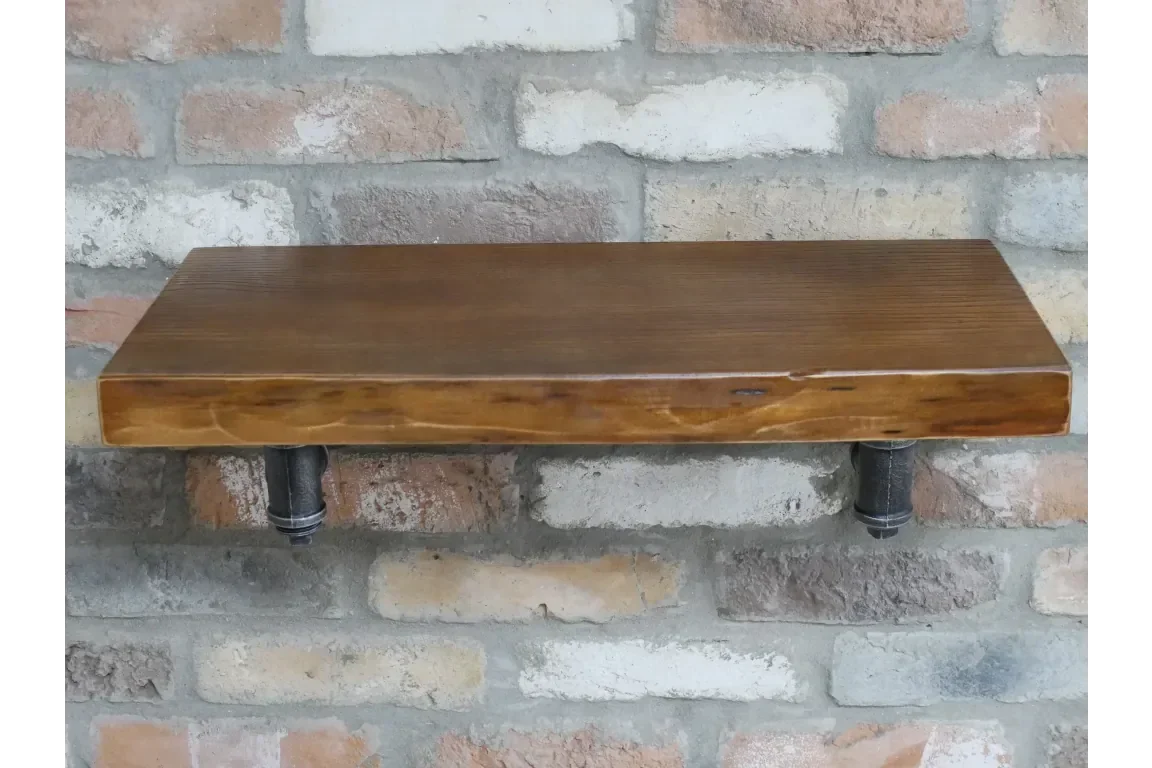 Solid wood wall shelf with industrial metal brackets mounted on brick wall