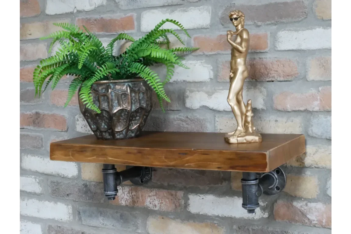 industrial pipe shelf with dark wood, plant pot and gold-tone statue on brick wall