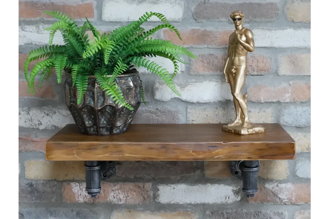 wooden industrial wall shelf with potted fern and gold statue against brick backdrop