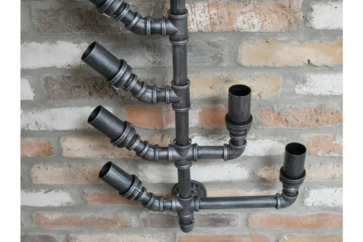 Industrial pipe wall candle holder with five metal sconces on exposed brick wall