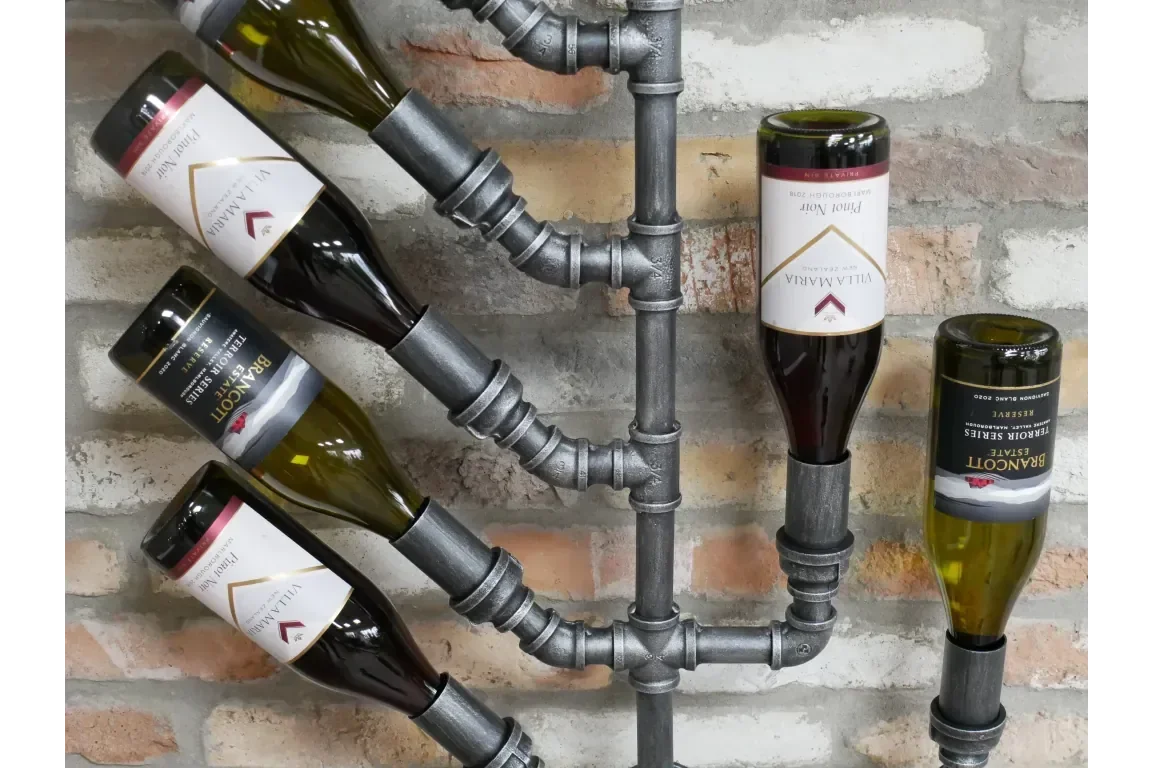 Industrial pipe wall wine rack holding six wine bottles on exposed brick background