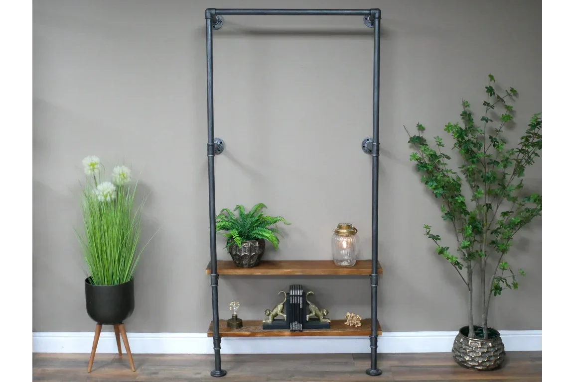 Industrial clothes rail with two wooden shelves and decorative plants against a neutral wall