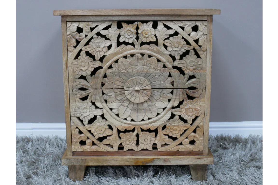 Carved wooden bedside table with floral pattern and natural finish on grey carpet
