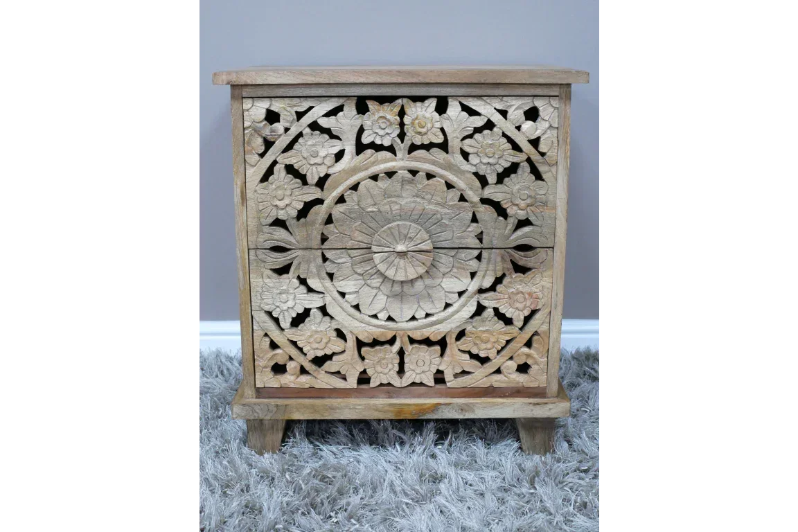 Wooden bedside table with carved floral design and two drawers on a grey rug